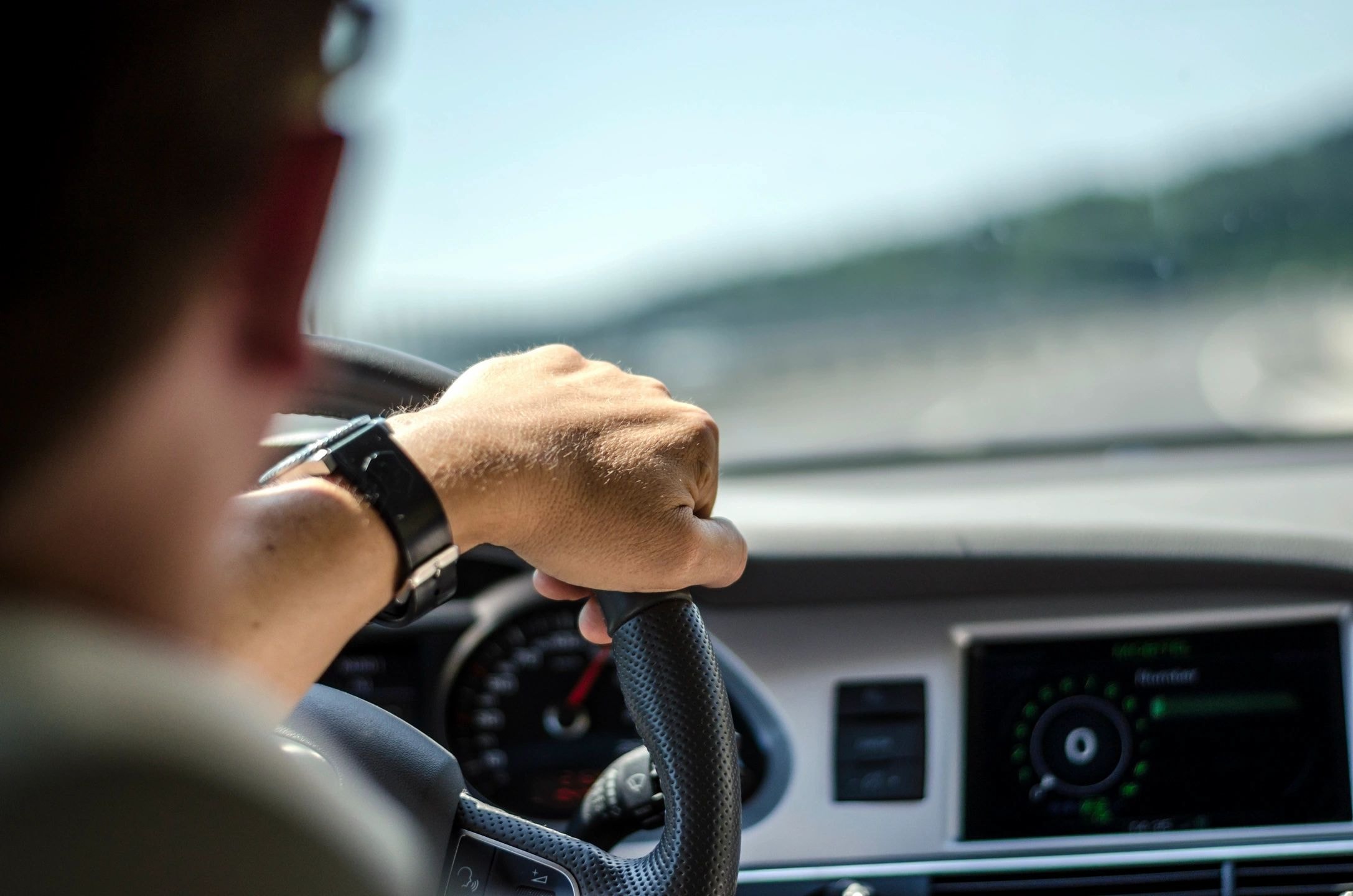Driver holding a steering wheel inside a vehicle
